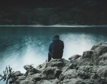 Lonely man sitting by a lake