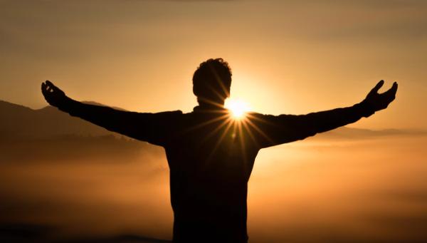 Man arms open looking at the sunrise