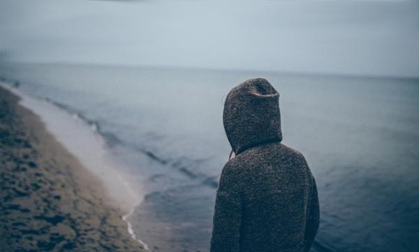 Sad person standing by the sea